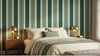 Chambre adulte cosy décorée d'un papier peint rayures vert sauge et crème associé à des meubles en bois naturel chaleureux