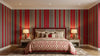 Chambre adulte raffinée ornée du Papier Peint Rayé Rouge et Blanc Harmonie sur le mur principal, avec des rayures régulières qui allongent visuellement la hauteur de la pièce