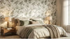 Chambre lumineuse habillée du papier peint oiseaux vert sauge Faustine sur toute une cloison, où les motifs d'oiseaux exotiques et de végétation luxuriante apportent une touche poétique et organique à l'espace