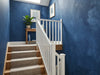 Papier peint couloir bleu indigo posé dans l'escalier d'une maison avec rampe blanche