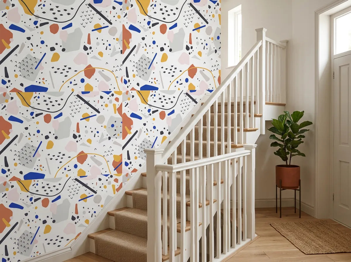 Papier peint couloir graphique posé dans l'escalier d'une maison avec rampe blanche et plante