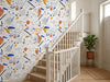 Papier peint couloir graphique posé dans l'escalier d'une maison avec rampe blanche et plante
