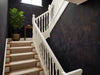 Papier peint couloir sombre posé dans l'escalier d'une maison avec rampe blanche et tapis d'escalier