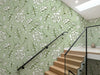 Papier peint fleuri vintage vert posé le long d'un escalier moderne avec rampe en verre