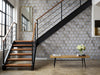 Papier peint géométrique hexagone gris et doré posé dans une cage d'escalier industrielle