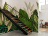 Papier peint jungle couloir à grandes feuilles posé derrière un escalier industriel en acier noir