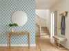 Papier peint motif géométrique treillis posé dans une entrée avec console en bois et miroir rond