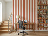 Papier peint rayures orange posé dans un bureau avec table en bois, fauteuil noir et bibliothèque