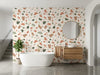 Papier peint terrazzo terracotta posé dans une salle de bain avec baignoire îlot et meuble vasque en bois