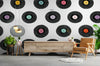 Papier peint disco vinyles posé dans un salon avec buffet en bois clair et fauteuil camel